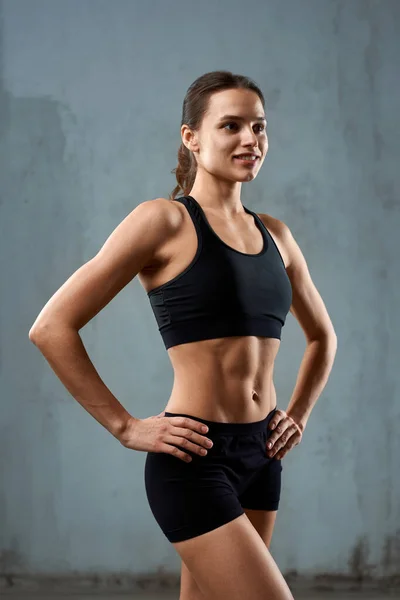 Sportkvinna poserar i sportkläder, isolerad på grå. — Stockfoto