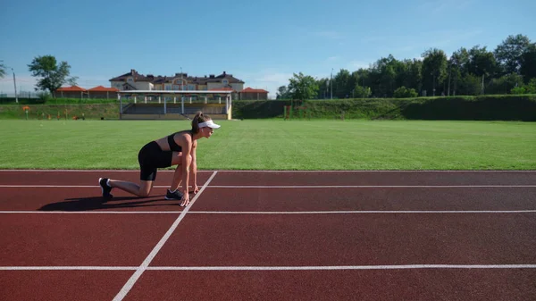 Mulher praticando posição de velocista em pista de corrida. — Fotografia de Stock