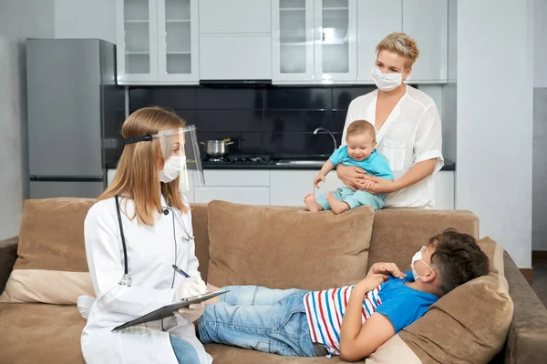 Kvinnlig läkare undersöker sjuka tonåring hemma — Stockfoto