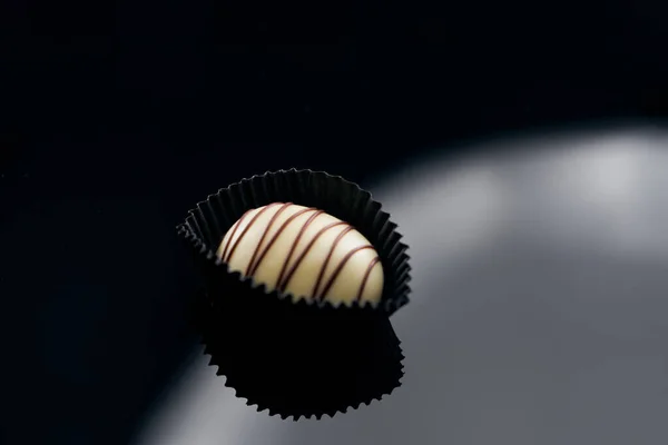 Pojedyncze czekoladowe cukierki na oszklonej powierzchni — Zdjęcie stockowe