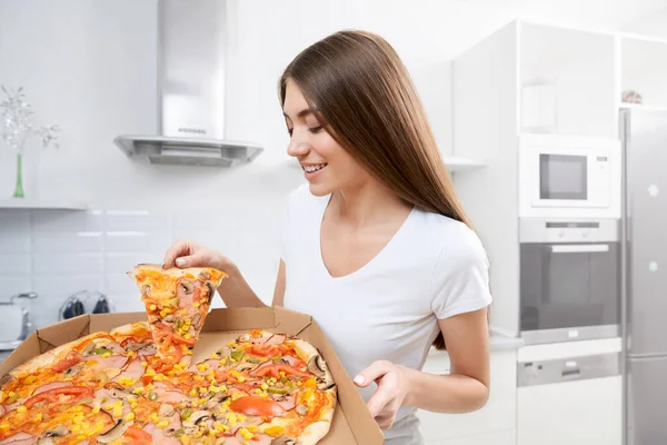 Νεαρή γυναίκα κρατά μεγάλη πίτσα στο σπίτι. — Φωτογραφία Αρχείου