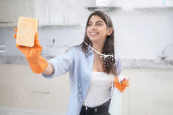 Glimlachende jonge vrouw wassen venster thuis. — Stockfoto