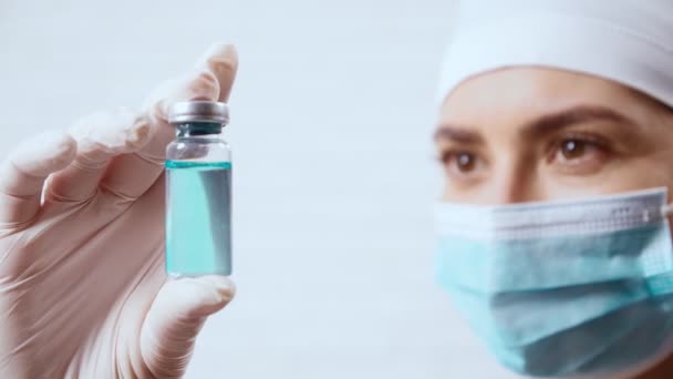 Új vakcinát tartalmazó injekciós üveget tartó fiatal nővér. — Stock videók