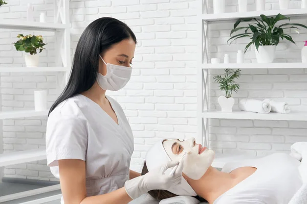 Beautician holding brush and doing procedure for woman. — Stock Photo, Image