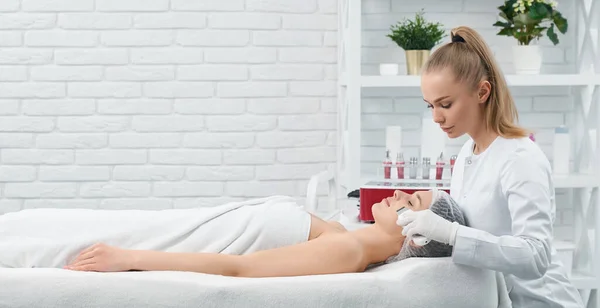 Mujer acostada en el sofá en el procedimiento para la cara en el salón de belleza. — Foto de Stock