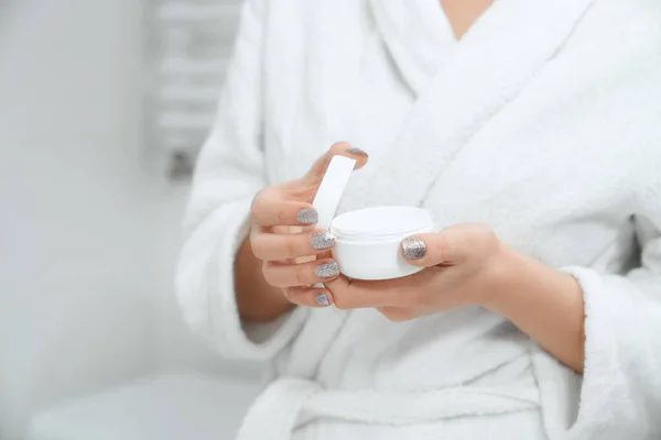 Mulher jovem segurando creme para o corpo ou rosto no banheiro. — Fotografia de Stock