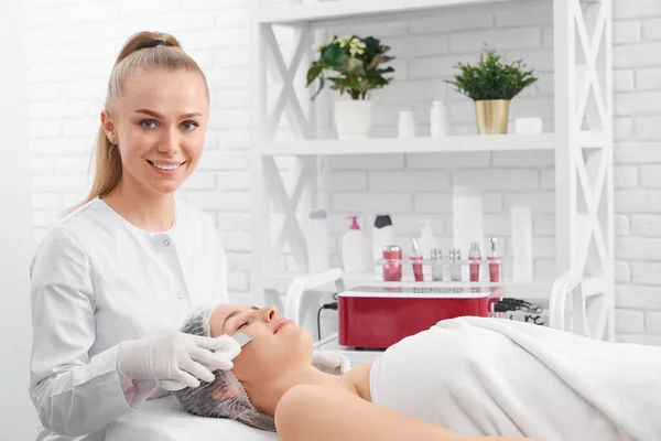 Sonriente esteticista haciendo procedimiento de belleza para el paciente. — Foto de Stock