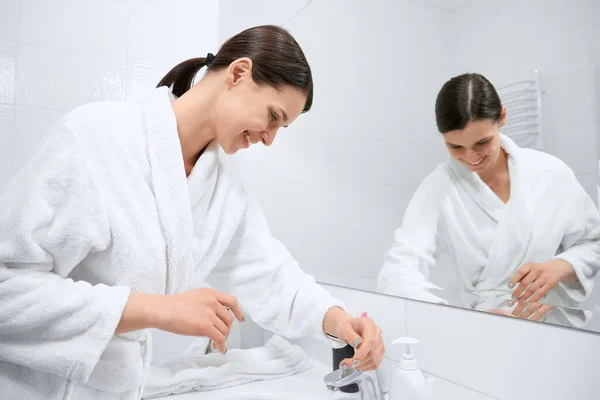 Brunette woman in white robe washing hands. — Stock Photo, Image