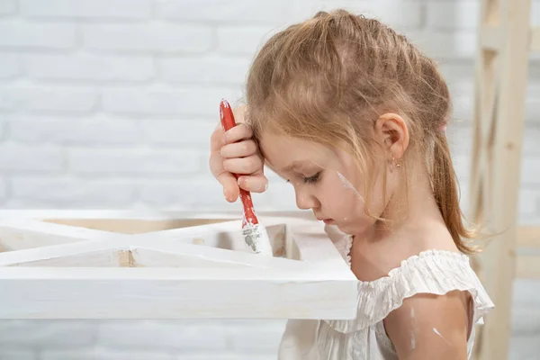 Petite fille mignonne peinture rack en bois à la maison. — Photo