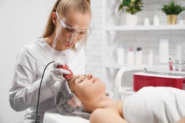  Koruyucu maskeli güzellik uzmanı kadın için masaj yapıyor..