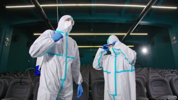 Men in protective suit, mask and rubber gloves at cinema — Stock Video