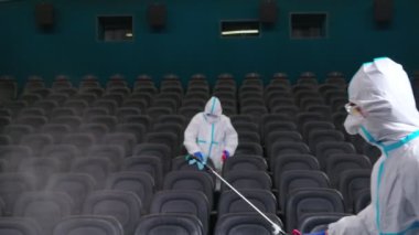 Temizlikçiler sinema salonunda dezenfektan püskürtüyor.