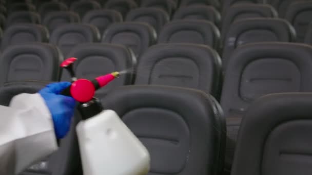 Мужчина в специальной одежде вытирает стулья для посетителей кинотеатра. — стоковое видео