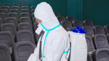 Koruyucu giysili ve maskeli bir adam lastik eldiven giyiyor.
