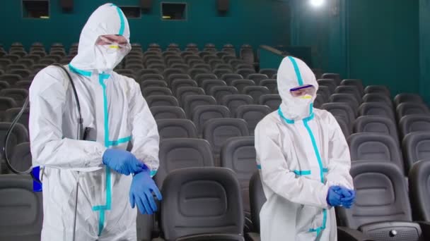 Men in protective suits preparing for disinfection at cinema — Stock Video