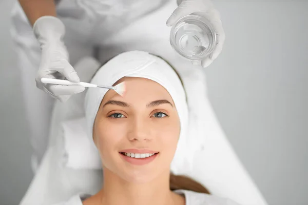 Smiling woman on beauty procedure in beautician.