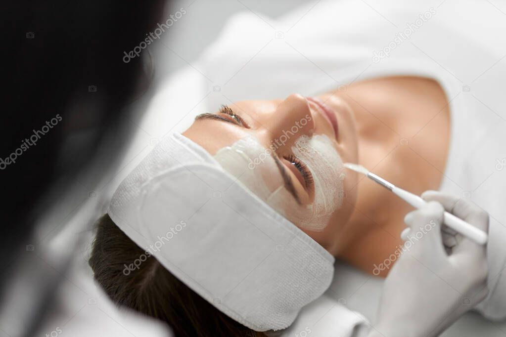 Young woman on procedure peeling face in beauty salon. 