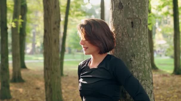 Mulher alegre relaxante no parque durante o treino — Vídeo de Stock