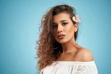 Kulağının arkasında çiçek olan güzel bir kadın.