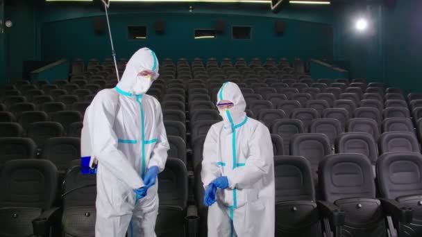 Медицинские работники в химическом костюме для дезинфекции кинотеатра — стоковое видео