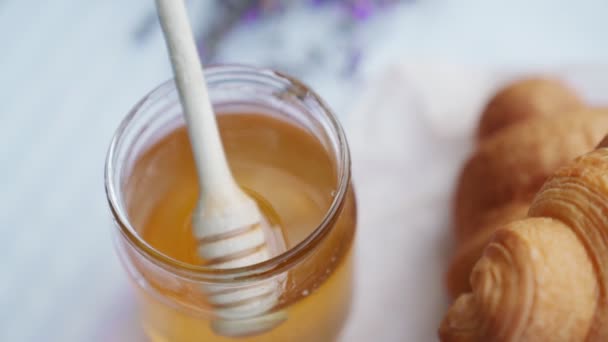 Croissants y miel en la mesa en el campo de lavanda. — Vídeo de stock