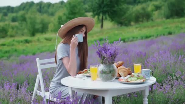 Žena drží šálek kávy v levandulovém poli. — Stock video