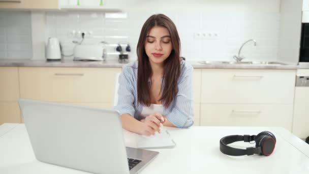Lächelnde junge Frau, die zu Hause studiert oder online arbeitet. — Stockvideo