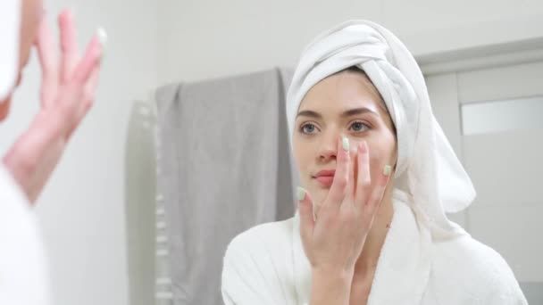 Mujer joven aplicar crema hidratante en la cara después de la ducha. — Vídeos de Stock