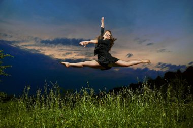 Güzel, genç, gülümseyen dansçı havada dans ediyor.