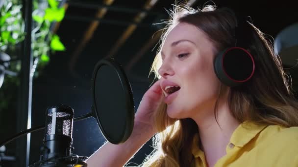 헤드폰을 끼고 스튜디오에서 새 노래를 녹음 하는 여성 가수 — 비디오