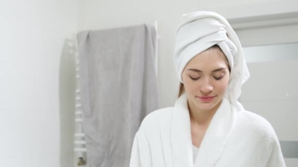 Femme mignonne en robe blanche avec serviette sur la tête brossant les dents. — Video