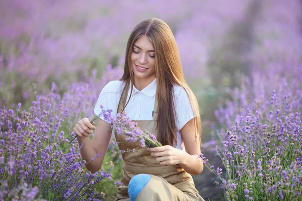 Hymyilevä nainen tekee kukkakimpun laventeli alalla. — kuvapankkivalokuva