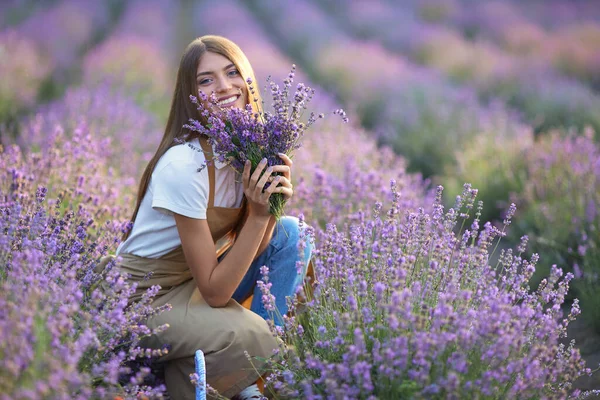 Femme souriante posant avec bouquet dans un champ de lavande. — Photo