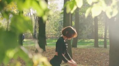 Sıska kadın şehir parkında çömeliyor.