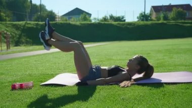 Kadın dışarıda bacak kaldırma egzersizi yapıyor..