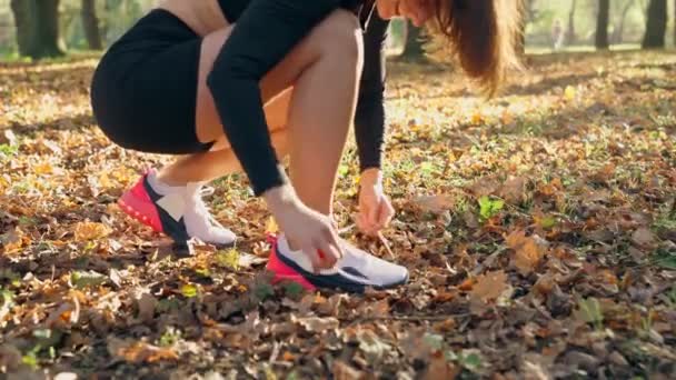 Giovane donna allacciatura lacci su scarpe da ginnastica sportive al parco — Video Stock