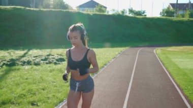 Stadyumda kulaklık takarak koşan bir bayan..