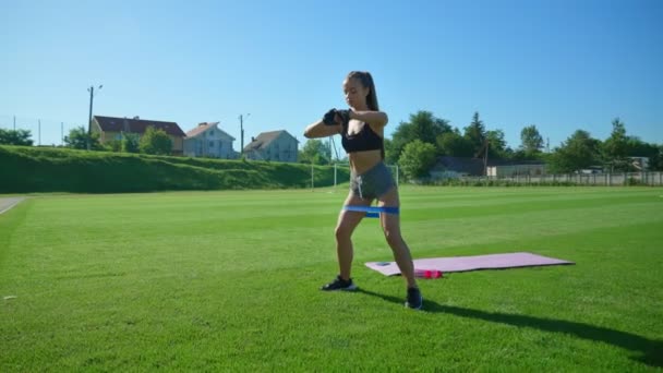 Kobieta ćwiczy przysiady za pomocą opaski fitness. — Wideo stockowe