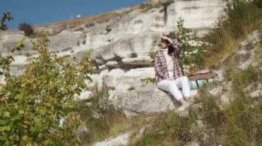 Rahat kadın sırt çantasıyla tepede oturuyor.