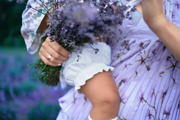 Unrecognizable woman holding baby and lavender bouquet. — Stock Photo, Image