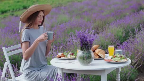 Женщина пьет кофе на лавандовом поле. — стоковое видео