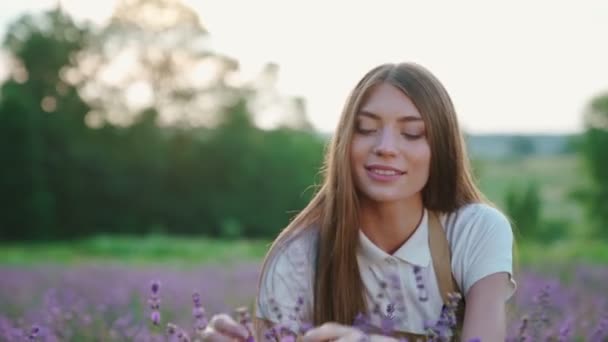 Улыбающаяся женщина сидит на лавандовом поле. — стоковое видео
