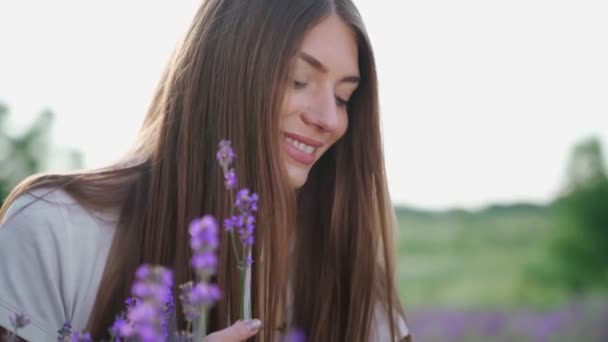 Menina sorrindo buquê cheirando no campo de lavanda. — Vídeo de Stock