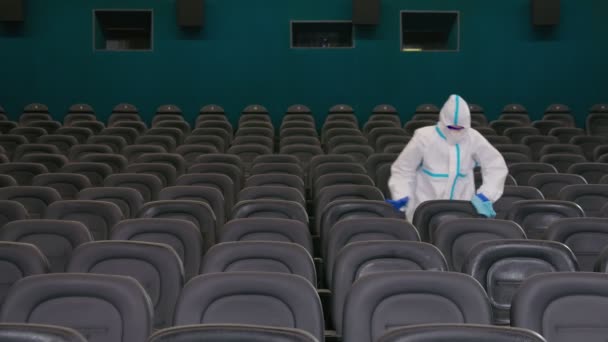 Trabajador limpiando sillas con desinfectantes en el cine. — Vídeos de Stock