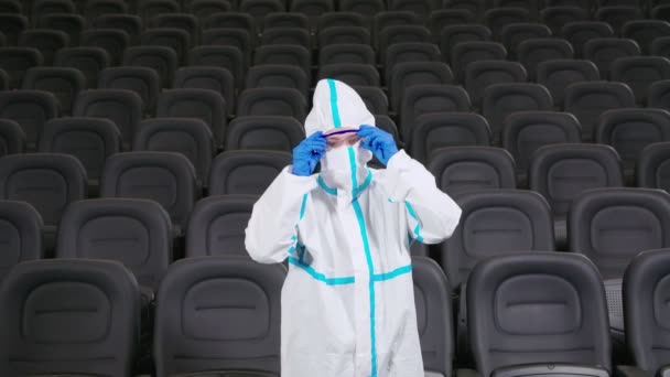Mannelijke persoon in beschermende kleding desinfecterende bioscoop — Stockvideo