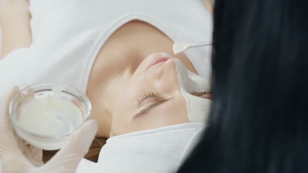 Косметолог надевает маску для лица для женщин. — стоковое видео