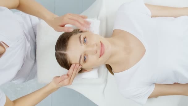 Esteticista profesional haciendo masaje en la frente y mejilla. — Vídeo de stock