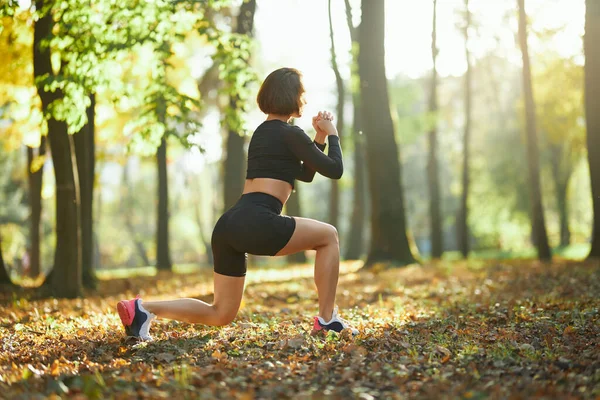 Kobieta sportowiec robi przysiady ćwiczenia w parku miejskim — Zdjęcie stockowe