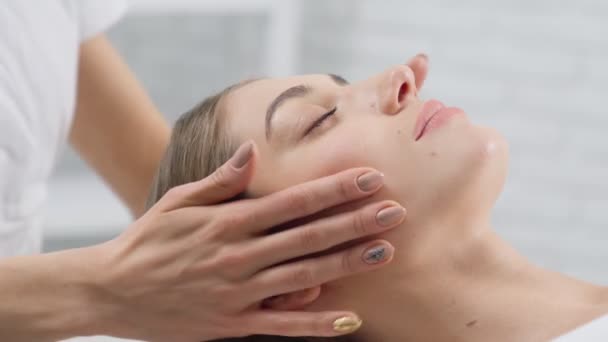 Krásná žena ležící na procedurální masáž obličeje. — Stock video
