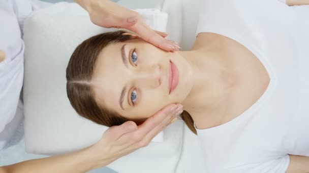 Kosmetyczka robi masaż twarzy dla młodej oszałamiającej kobiety. — Wideo stockowe